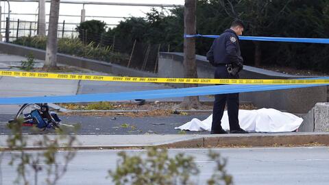 Un oficial de policía al lado de una de las víctimas y a p...